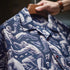 Close-up of a blue shirt with white graphic designs, held by a person.